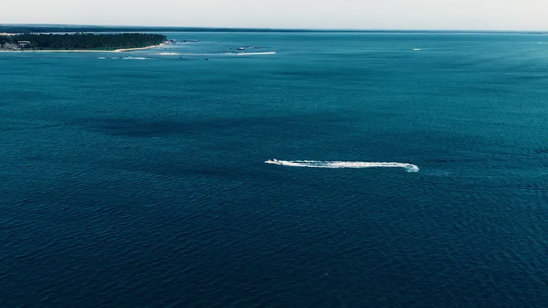 A speedboat wake across deep blue water at Pasikudah